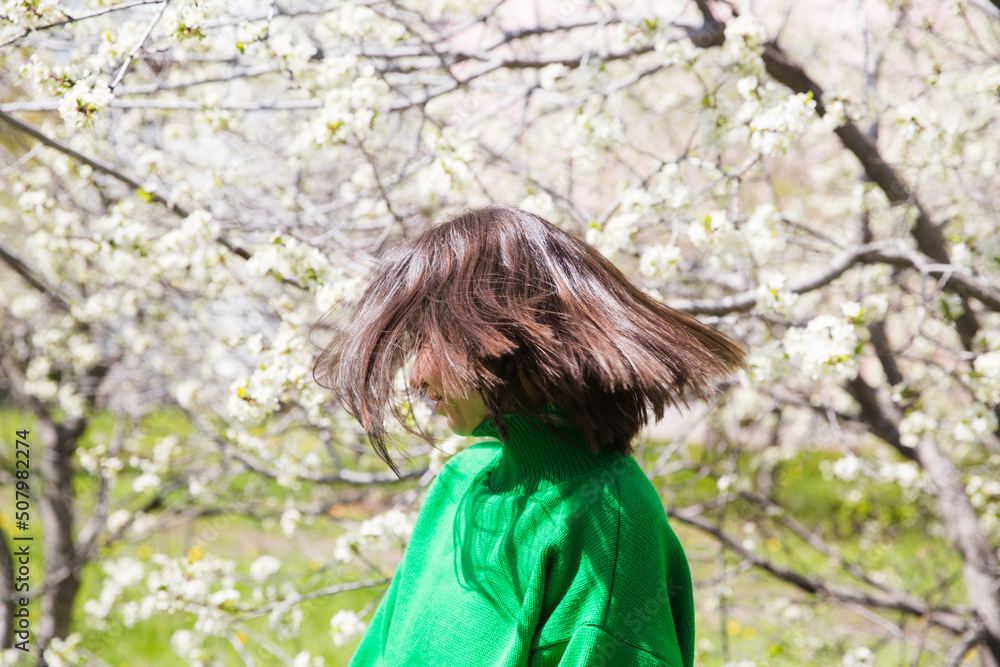 woman in green sweater with short hair blowing in the wind in flowering spring garden. Spring awakening. Slow life. Enjoying the little things. Dreaming of spring. woman in green sweater with short hair blowing in the wind in flowering spring garden. Spring awakening. Slow life. Enjoying the little things. Dreaming of spring.