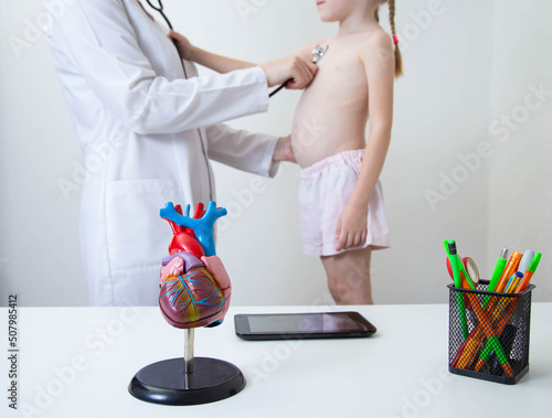 doctor pediatric cardiologist listening with stethoscope heart rate of a little girl 5 years old photo