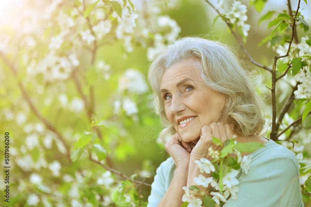 Beautiful senior woman posing near blooming tree Beautiful senior woman posing near blooming tree