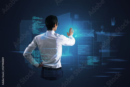Attractive young european businessman standing on abstract blue background with coding and tech information. Database, cloud computing and science concept. Double exposure.