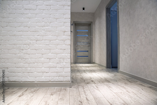 Modern renovation in the hallway, gray linoleum and white brick wall. Spotlights on the ceiling. Copy space for text