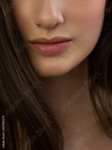 Cosmetics, makeup and trends. Bright lip gloss and lipstick on lips. Closeup of beautiful female mouth with natural lip makeup. Beautiful part of female face. Perfect clean skin in red light