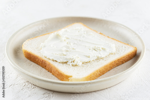 A slice of toast bread with cream cheese in a plate.