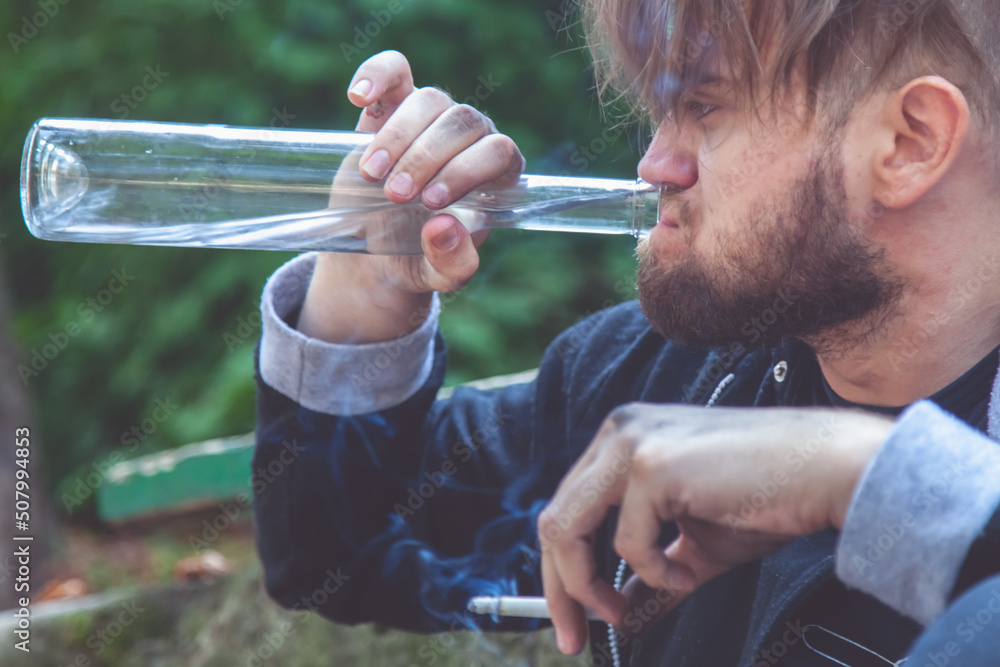 Portrait of man drinking vodka and smoking cigarette. Drunk young