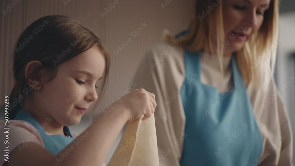 pretty little girl is helping mother in kitchen, child is playing with raw pastry and smiling charmingly pretty little girl is helping mother in kitchen, child is playing with raw pastry and smiling charmingly
