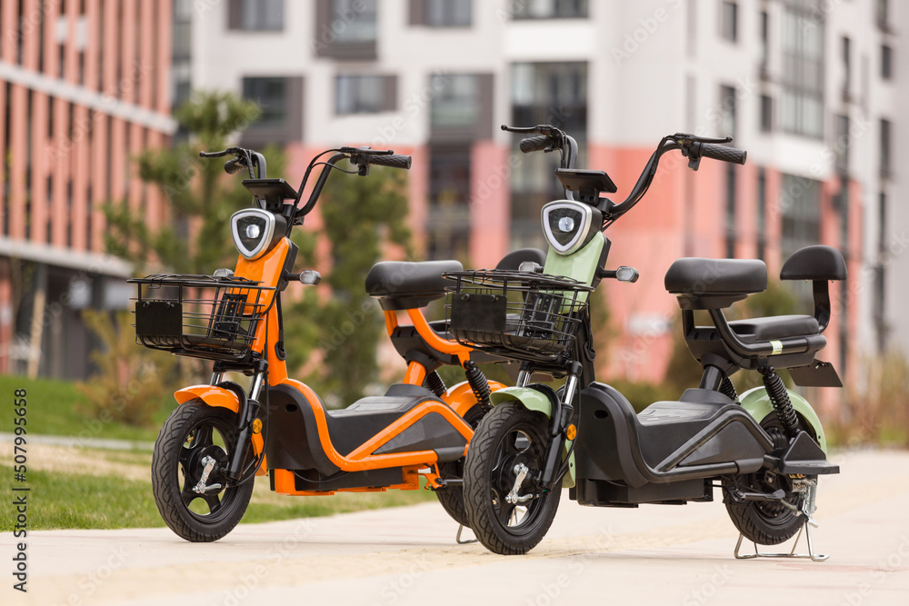 orange and mint electric scooters with chair on the background of a modern residential area