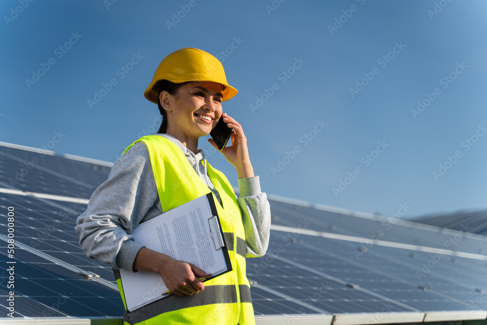 Woman engineer in helmet talking on mobile phone getting advice from the governance working on construction site of solar power plant. Agreement concept Woman engineer in helmet talking on mobile phone getting advice from the governance working on construction site of solar power plant. Agreement concept