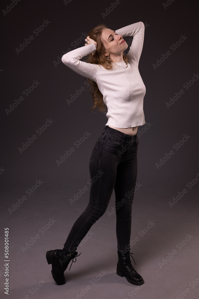 Obraz premium Portrait of playful girl making faces. Mixed emotions on face: fooling, flirting and smiling. Sitting, black background.