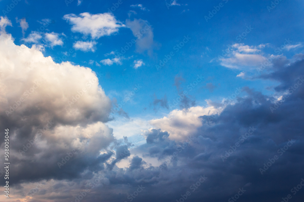 white cumulus clouds on a blue sky. beautiful nature background in evening light