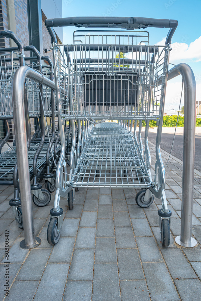 Empty stainless steel modern shopping carts standing at the supermarket in a row in line unused. Empty stainless steel modern shopping carts standing at the supermarket in a row in line unused.