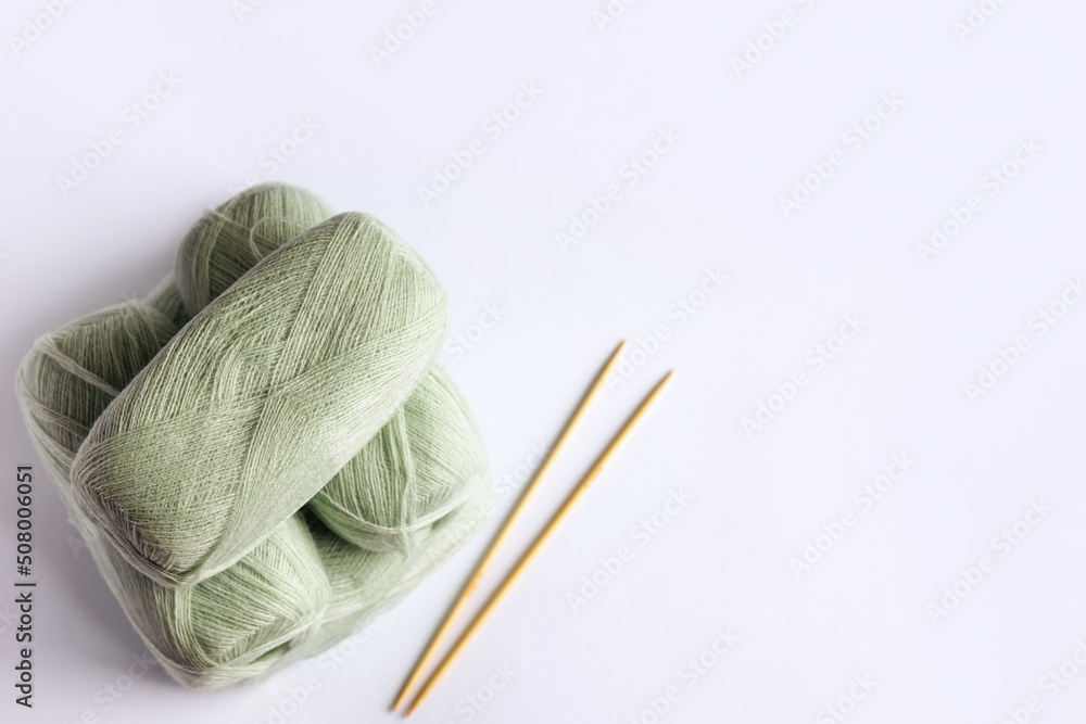 Light green yarn threads with knitting needles on a blue background for knitting. Flat lay Light green yarn threads with knitting needles on a blue background for knitting. Flat lay