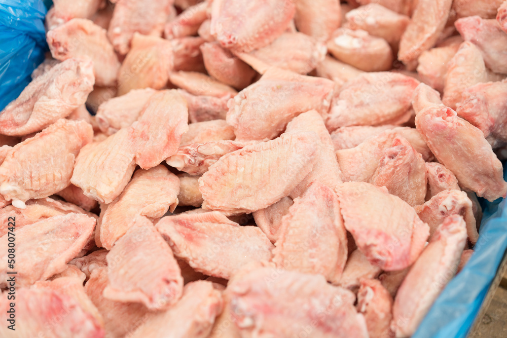 Frozen chicken wings for barbecue at market stall as background with copy space