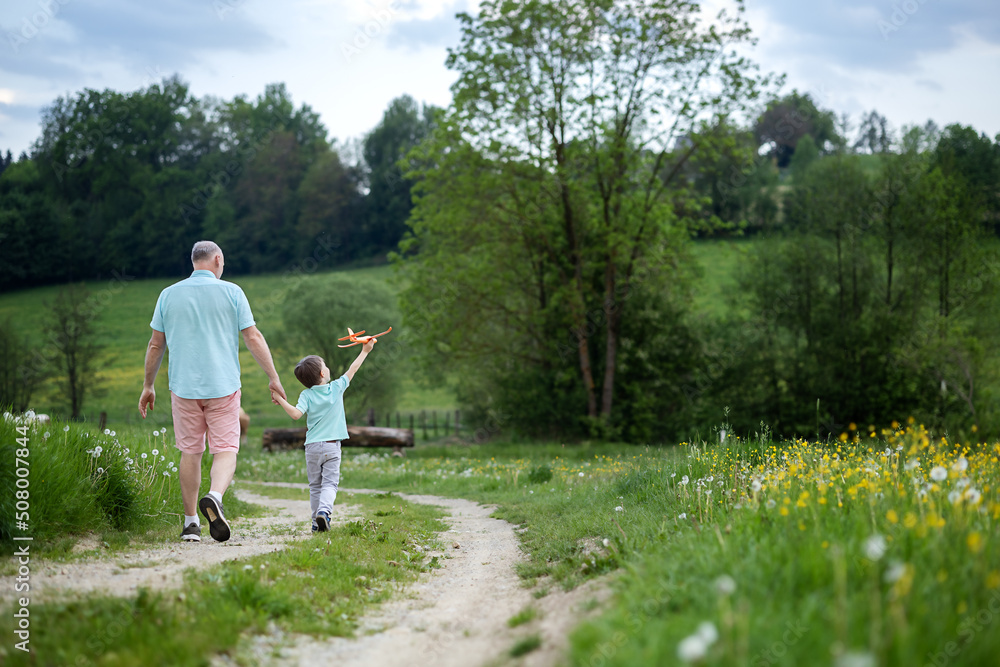 a five-year-old boy walks with his grandfather on a rural road and they talk a five-year-old boy walks with his grandfather on a rural road and they talk