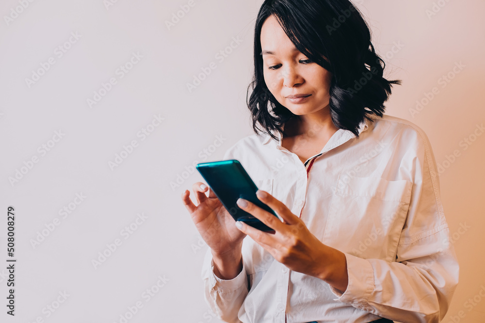 asian business woman dressed in white shirt uses smartphone reads messages on white background asian business woman dressed in white shirt uses smartphone reads messages on white background