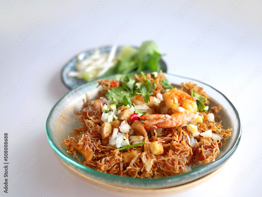 Thai Crispy rice noodles in traditional style with shrimp, Royal recipe, in special plate and vegetable with copy space and white background Thai Crispy rice noodles in traditional style with shrimp, Royal recipe, in special plate and vegetable with copy space and white background