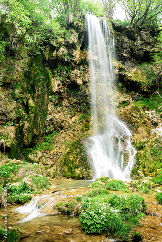 Small mountain waterfall on the rocks covered with moss in the forest