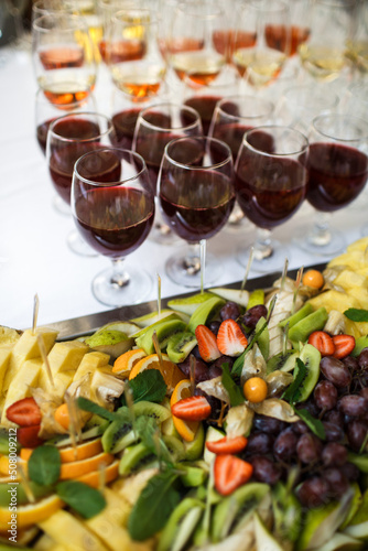 Assorted fruits and rows of glasses with wine on the festive table