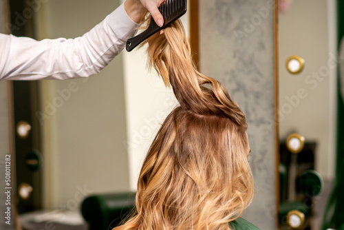 Professional hair care. Young female blonde with long hair receiving hairstyling in a beauty salon