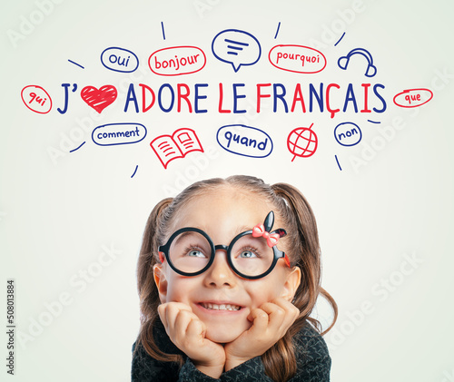 Beautiful cute little girl with eyeglasses looking at I Love French text and illustrations. English: I Love French. Foreign language learning concept.