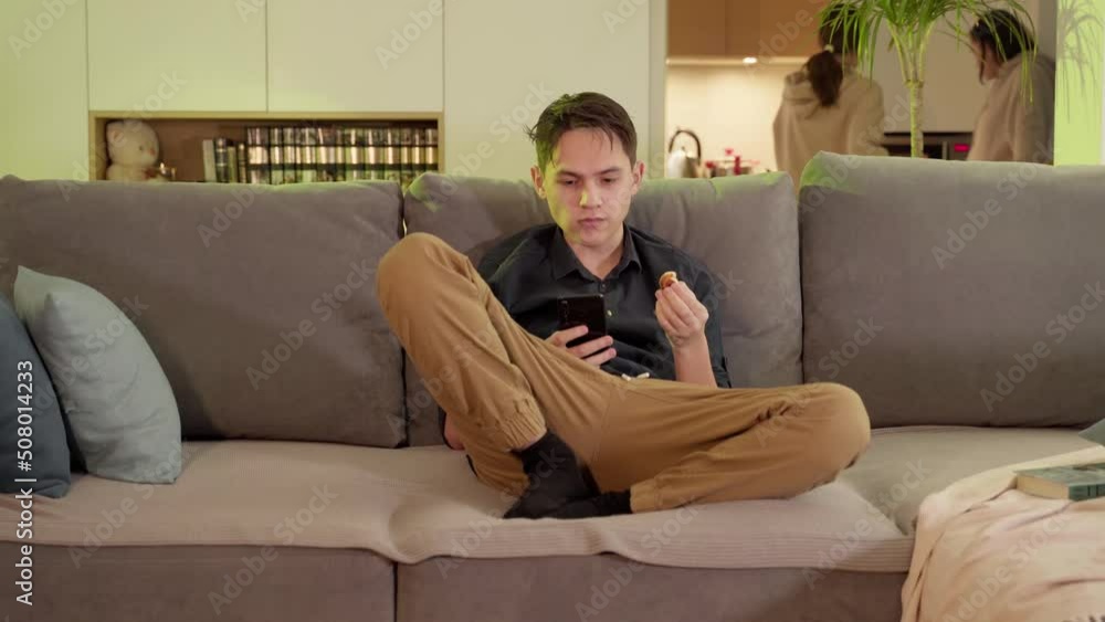 A guy in hearing aids sits with a phone on the couch. A guy in hearing aids sits with a phone on the couch.