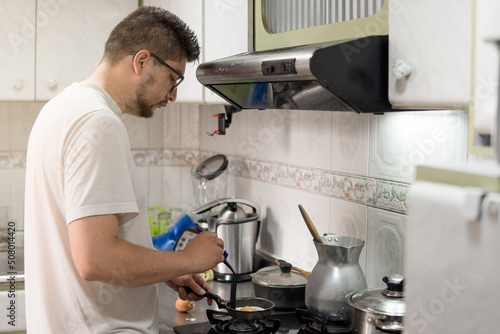 latin man cooking a fried egg in a typical colombian kitchen