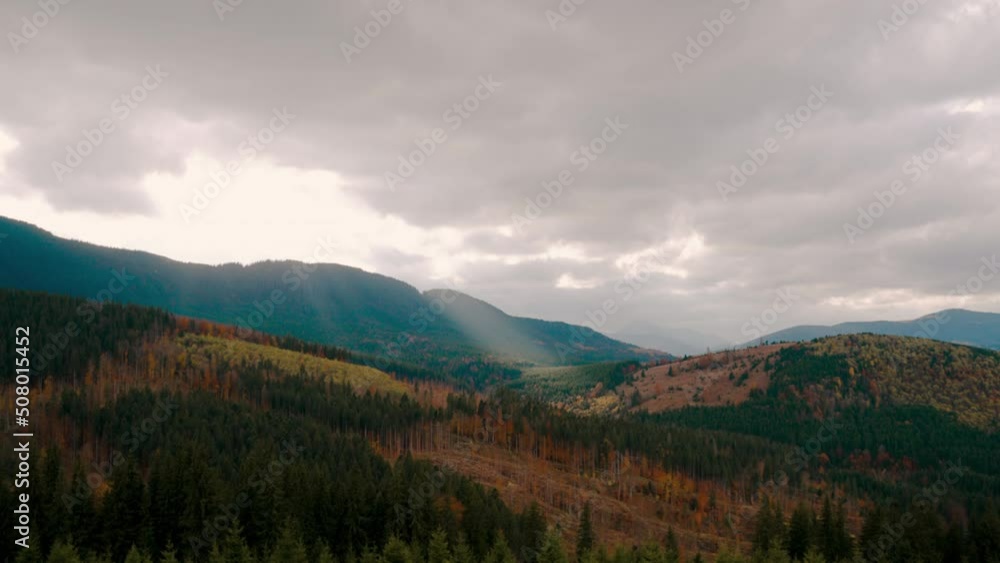 Autumn landscape of a mountain range covered with vegetation. Heavy gray clouds in the sky, through which the sun's rays break through. The concept of peace, tranquility, balance and relaxation Autumn landscape of a mountain range covered with vegetation. Heavy gray clouds in the sky, through which the sun's rays break through. The concept of peace, tranquility, balance and relaxation