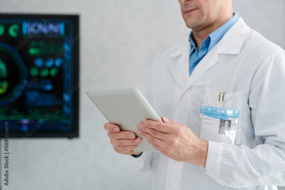 Close-up of mature doctor in white coat using digital tablet for online work Close-up of mature doctor in white coat using digital tablet for online work