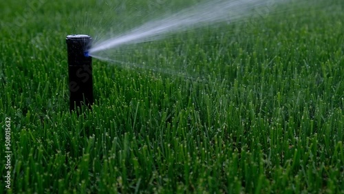 Automatic garden irrigation system watering lawn. Savings of water from sprinkler irrigation system with adjustable head. Automatic equipment for irrigation and maintenance of lawns, gardening.