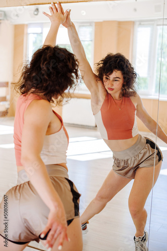 Young woman dancer performing a dance with mirror reflection in the dance studio