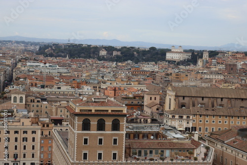 ROME, ITALY - February 05, 2022: Panoramic view around the Colosseum in city of Rome, Italy. Cold and gray sky in the background. Macro photography of the green parks with the old buildings. © yohananegusse