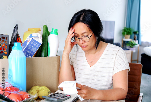 Woman upset headache depressed from family cost higher doing accounting holding receipts from supermarket with calculator by rising grocery prices and surging cost as an inflation financial crisis. photo