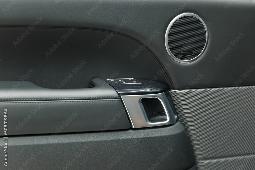 The concept of detailing. Black leather car door panel. Chrome door handle. The interior of the