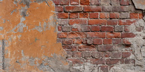 Dirty old red brick wall with cracks and orange paint. 