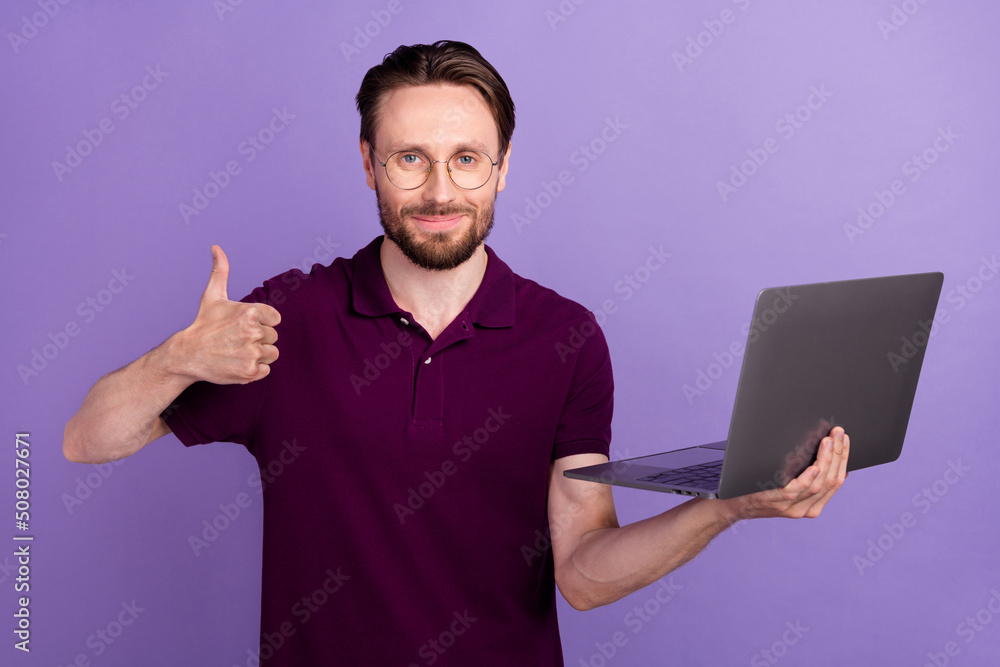 Photo of young man use laptop show figner thumb-up approve good ideal isolated over violet color background Photo of young man use laptop show figner thumb-up approve good ideal isolated over violet color background