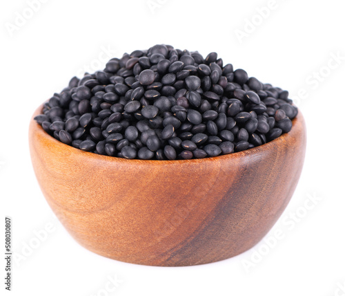 Obraz na płótnie Black lentils in wooden bowl, isolated on white background