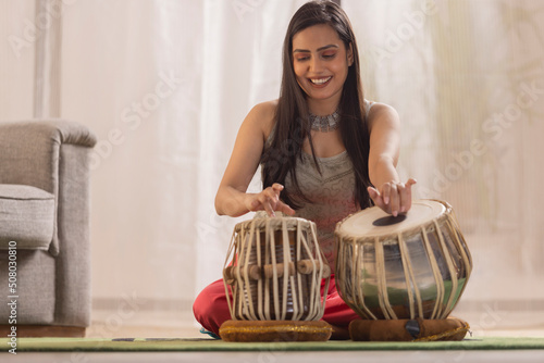Portrait of young woman playing Tabla at home photo