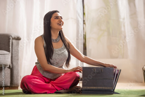 Portrait of young woman playing harmonium at home