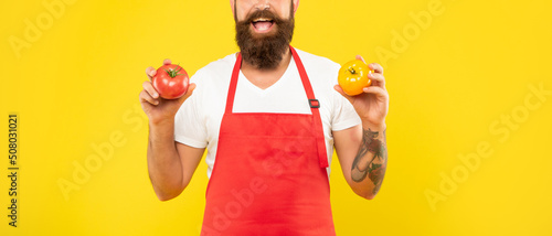 Canvastavla Happy man crop view in cooking apron holding red and yellow tomatoes yellow back