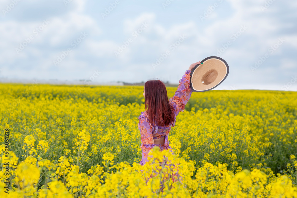 Fototapeta premium Young woman walking through a field of flowers