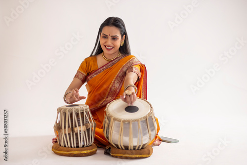 Portrait of cheerful woman in traditional outfit playing tabla