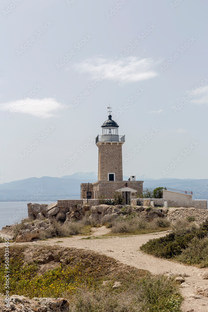 Old, stone lighthouse against the backdrop of the sea and mountains