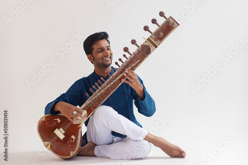 Portrait of cheerful young man playing sitar