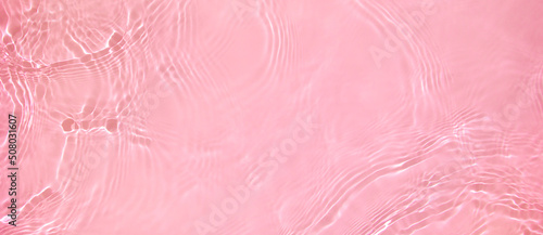 Abstract summer banner background Transparent pink clear water surface texture with ripples, splashes. Water wave in sunlight, copy space, top view. Cosmetics moisturizer micellar toner emulsion