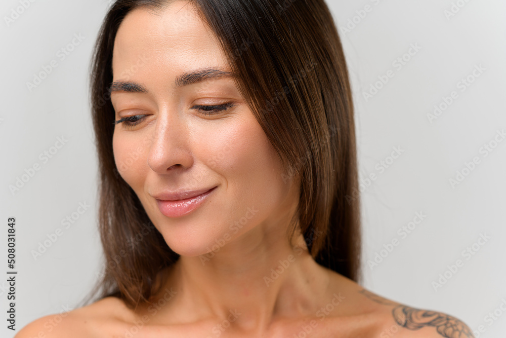 Portrait view of the attractive young woman with tattoos at her naked shoulders looking away with pleasure smile. Beauty concept Portrait view of the attractive young woman with tattoos at her naked shoulders looking away with pleasure smile. Beauty concept
