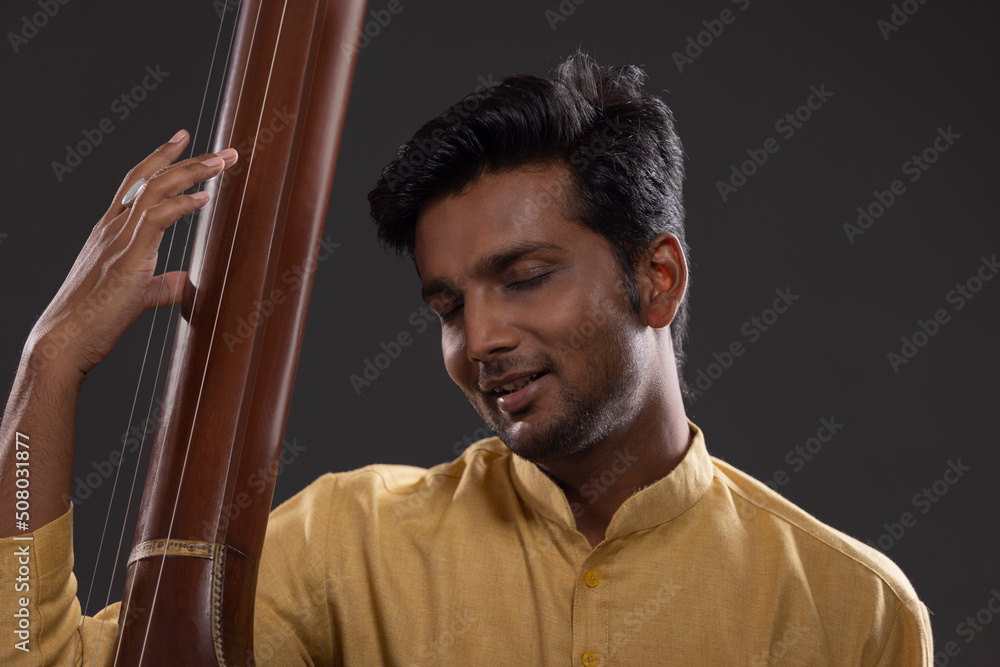 © IndiaPix - Close-up view of a male musician performing with Tanpura at concert