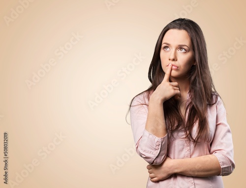 Thoughtful woman keeps hand on chin looks pensively