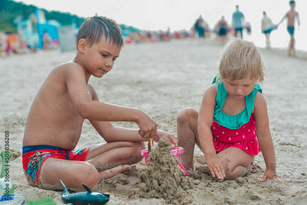 Brother and sister making sand castle on the beach Brother and sister making sand castle on the beach