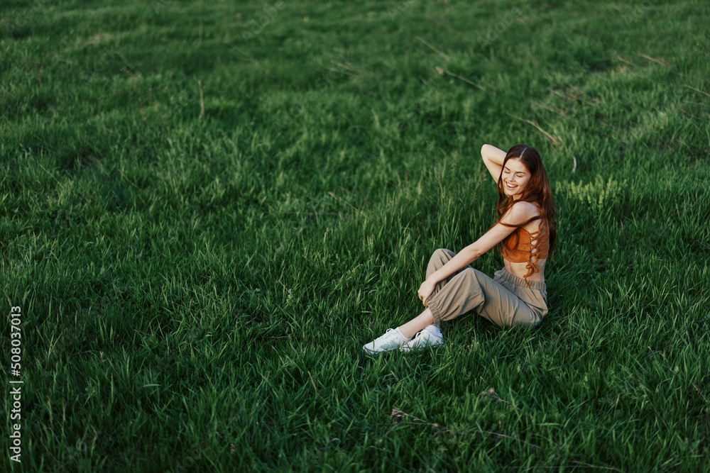 A woman enjoying the outdoors sitting in the park on the green grass in her casual clothes lit by the bright summer sun without mosquitoes A woman enjoying the outdoors sitting in the park on the green grass in her casual clothes lit by the bright summer sun without mosquitoes