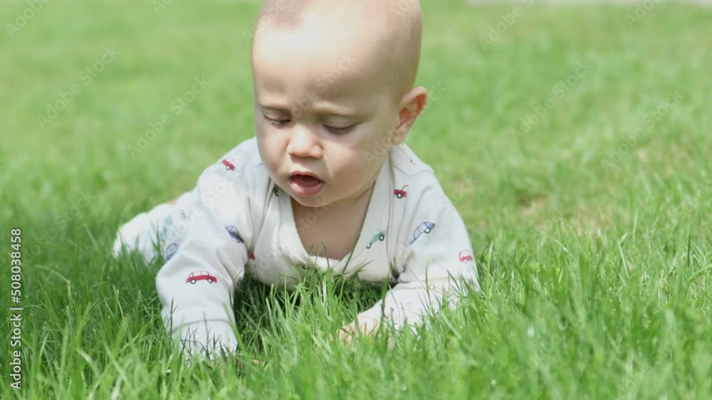 adorable sweet baby infant lying in green grass field outdoors in sunny day. child kid baby learning nature, air, meet environment. happy childhood, early education concept. healthy lifestyle. summer adorable sweet baby infant lying in green grass field outdoors in sunny day. child kid baby learning nature, air, meet environment. happy childhood, early education concept. healthy lifestyle. summer