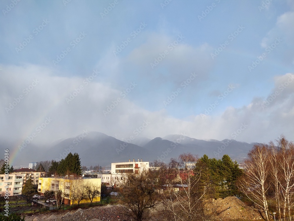 Fototapeta premium Rainbow in the city over eht hills and houses. Slovakia